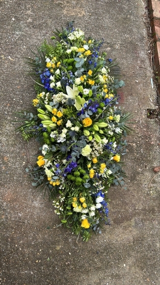 Coffin spray made of blue, yellow, green and white flowers suitable for a man done by funeral florist in Bromley, Beckenham, Croydon, Orpington, Chislehurst, Petts Wood
