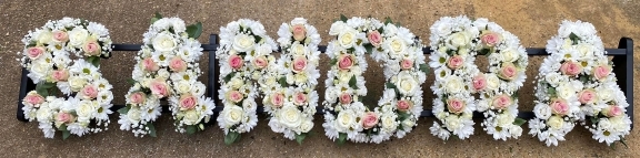 mixed white wild looking funeral wording with splash of colour made by florist in Bromley, Kent